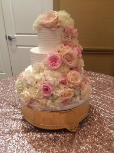 white, three tiered cake with pink and cream flowers