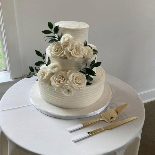 beautiful two tier cake with white buttercream frosting and white roses